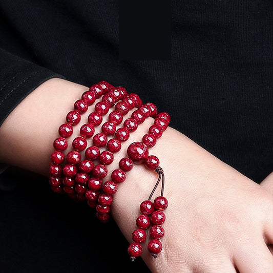 The 108 - bead crystal cinnabar bracelet worn on a wrist, showing its multi - loop style and the text "Protection" nearby, symbolizing its meaning.