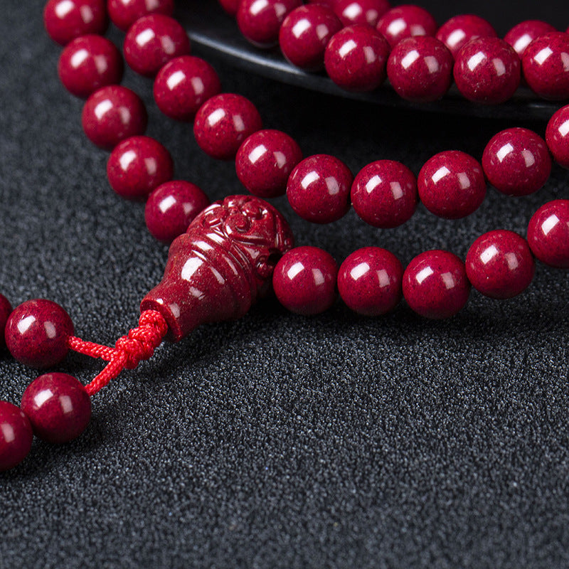 Laid on a black plate, the 108 - bead cinnabar bracelet features vivid red beads and a unique carved pendant, a testament to fine craftsmanship.