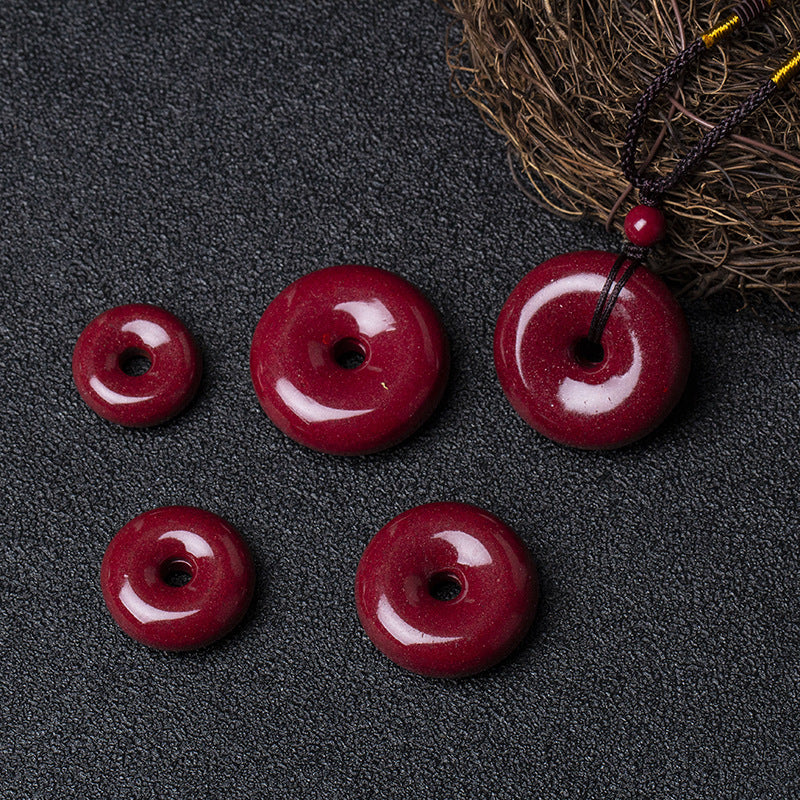 A set of cinnabar donut pendants in different sizes, laid out on a dark - colored surface with a twig beside them.