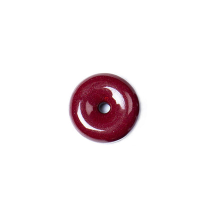 A cinnabar donut pendant against a white background, clearly presenting its circular shape and the central hole.