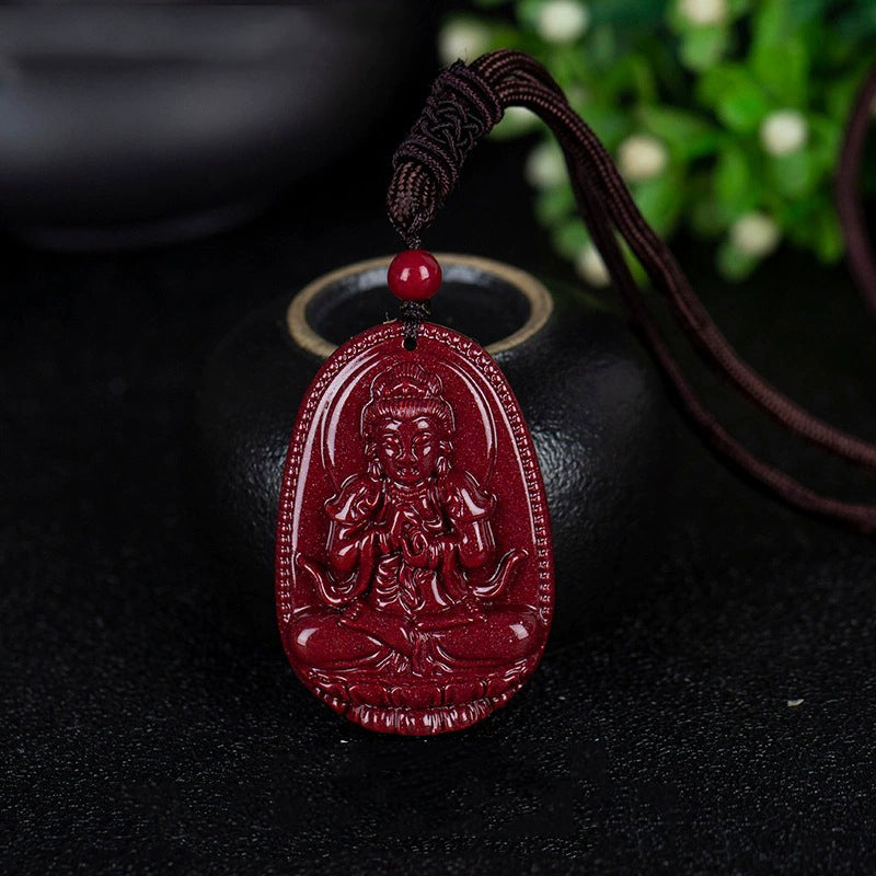 A cinnabar pendant depicting a Buddha, placed on a black surface. The intricate carving details are clearly visible.