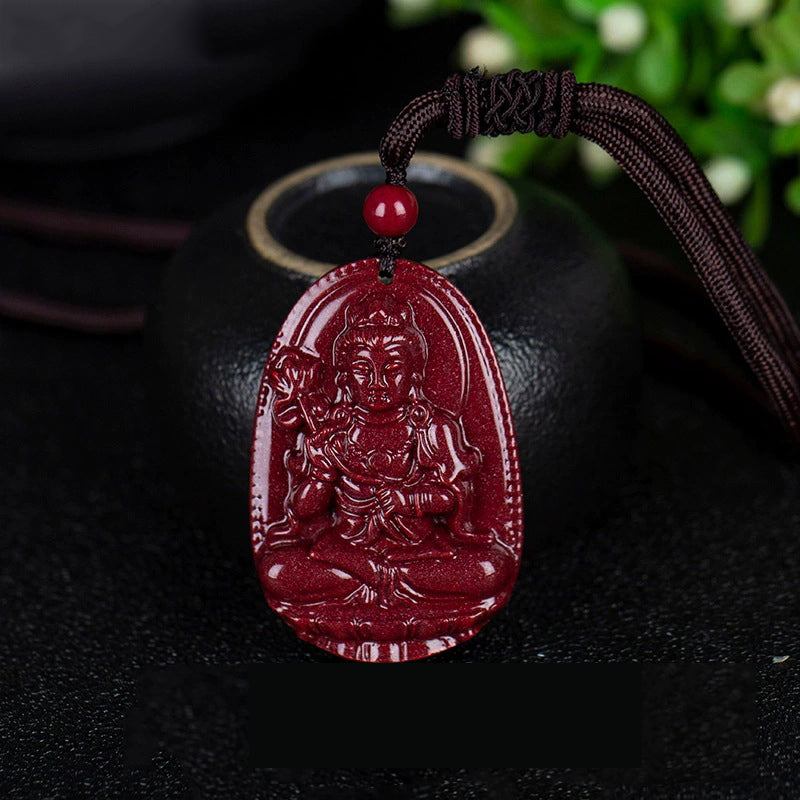 A cinnabar pendant with a carving of a deity in a seated pose, placed beside a black pot. The rich red color of the cinnabar is eye - catching.