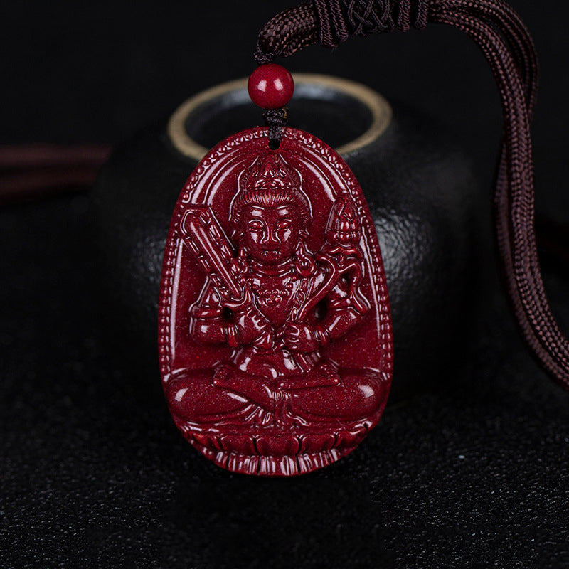 A cinnabar pendant with a carving of a deity riding an animal, placed beside a black pot. The oval shape of the pendant is distinct.