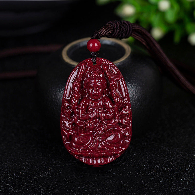 A cinnabar pendant featuring a deity holding two objects, hanging beside a black pot. The polished surface of the cinnabar is shiny.